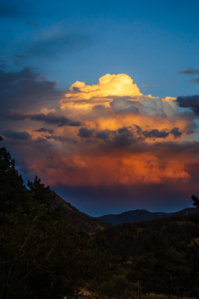 A cumulus congestus cloud lit up in rosy red and yellow sunset colors