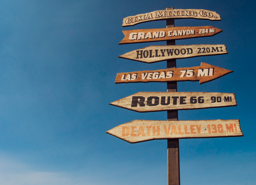 An Old Western signpost pointing to different famous locations such as the Grand Canyon and Hollywood.