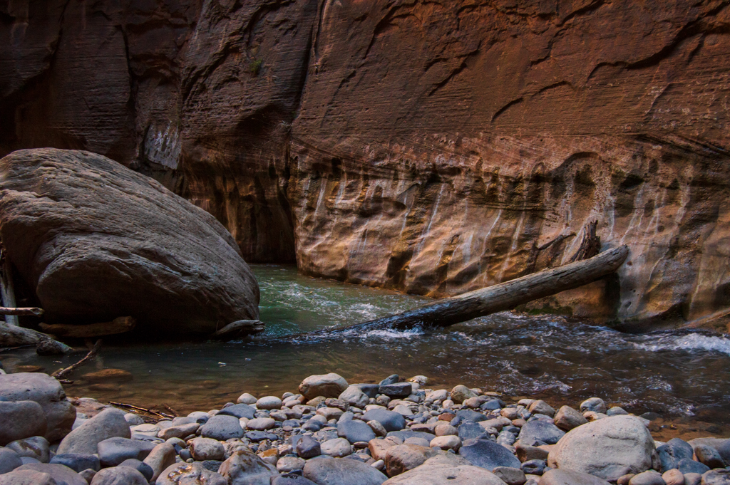 A deep, green section of the Virgin River, with water rushing over a log.