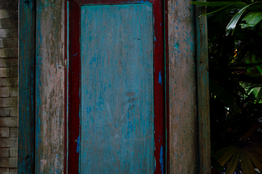 A worn wooden door painted in bright blue and red