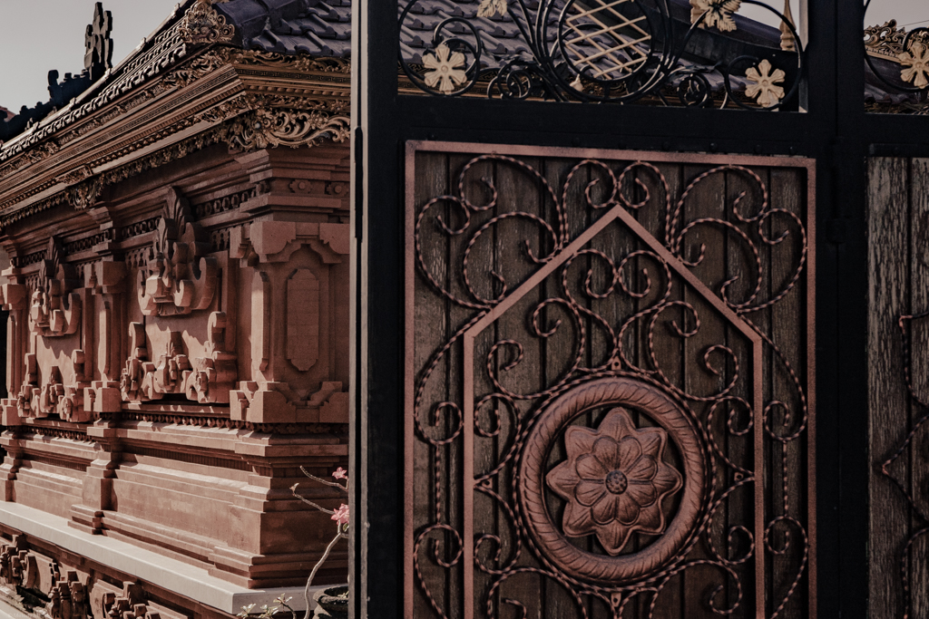 A metal gate adorned with flowers, guarding a large building