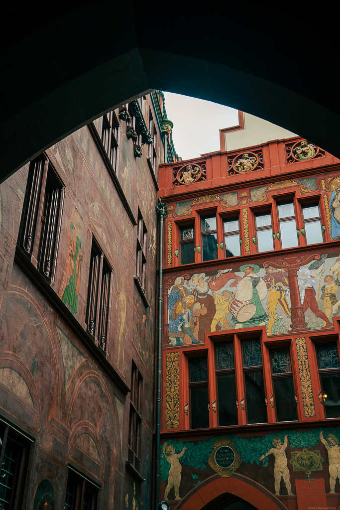 View of the murals on the inside walls of the Rathaus through an archway