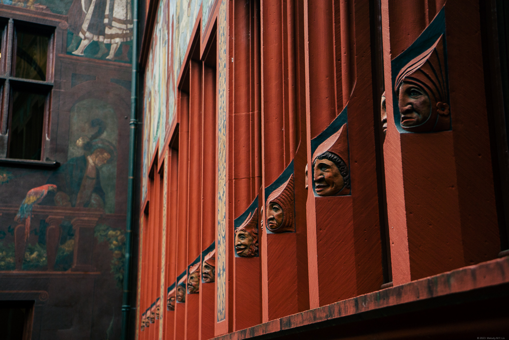 Carvings of different faces on the beams of the windows