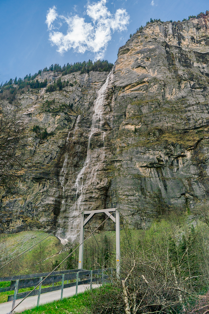 A small, cable-stayed bridge next to a waterfall