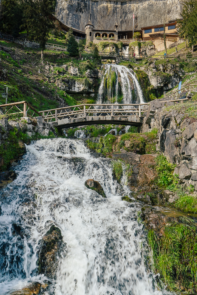 A wooden footbridge crosses over a series of falls cascading down the mountain