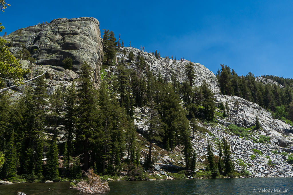 A huge granite wall rises over the lake