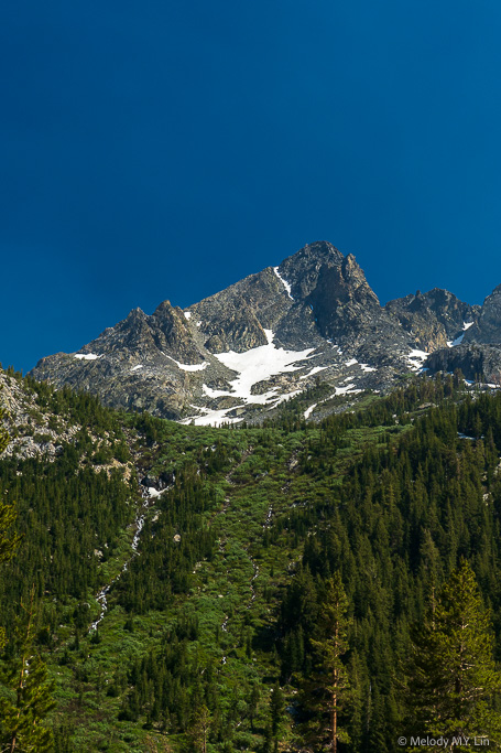 A mountain peak with waterfalls running down the sides.